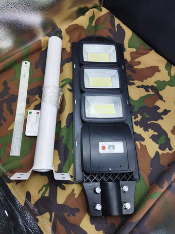 Black three-panel solar street lamp with LED panels, mounting pole, and remote control