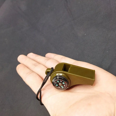 Olive-drab plastic survival whistle with integrated compass and black lanyard