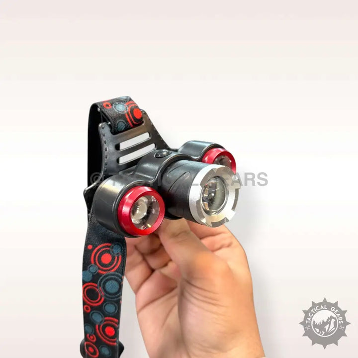Black adjustable rechargeable headlight with three red-rimmed lights held by hand