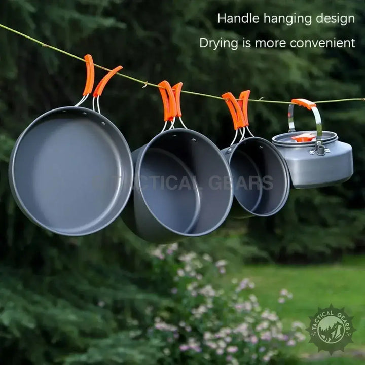 Camping cookware set with orange foldable handles and frying pan hanging to dry