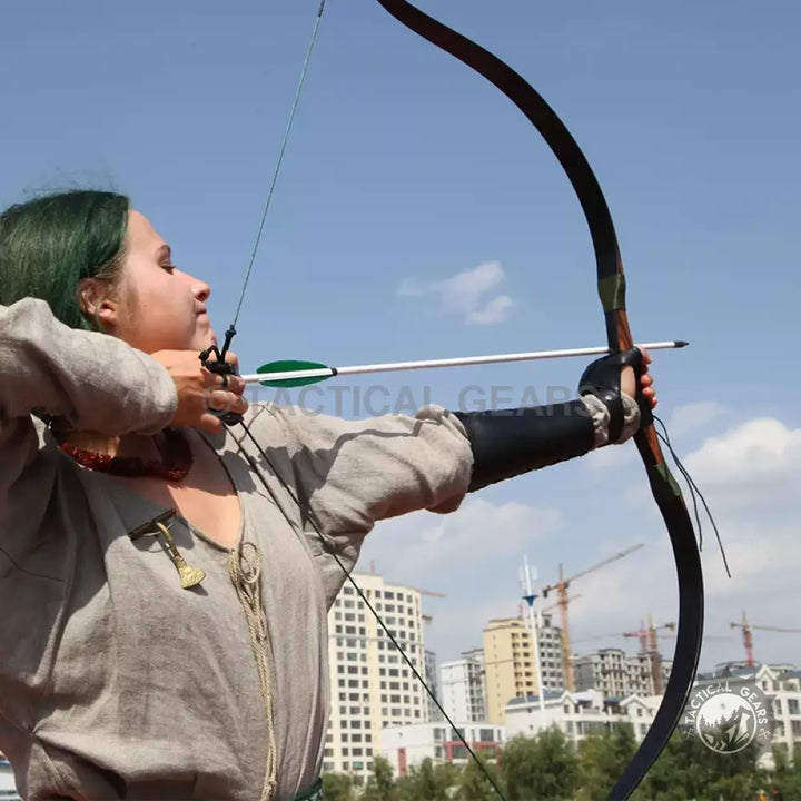 Woman drawing a recurve bow wearing an archery bow arm guard and finger tab