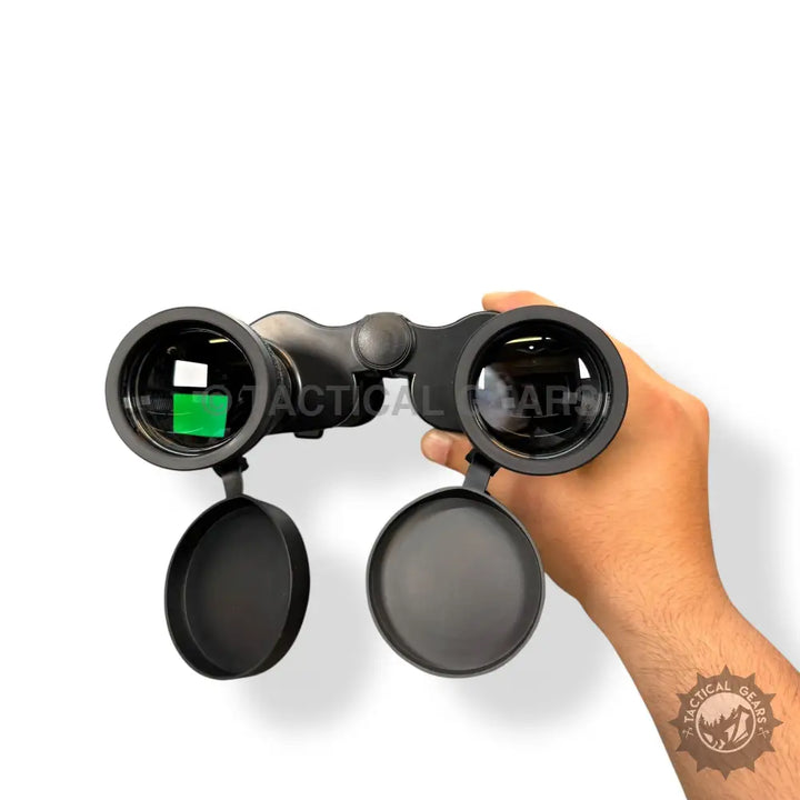 Black Benko 26x50 binoculars with lens caps held in hand for outdoor viewing