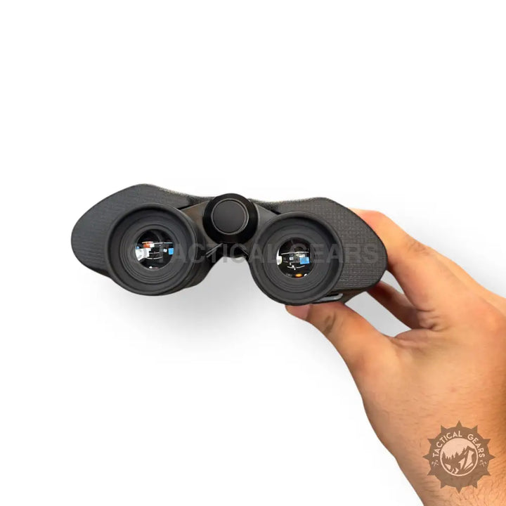 Black 10x50 binocular with textured grip and reflective lenses held in hand