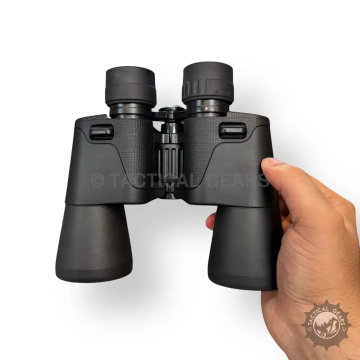 Black 10x50 binoculars with textured grip held in hand for outdoor viewing