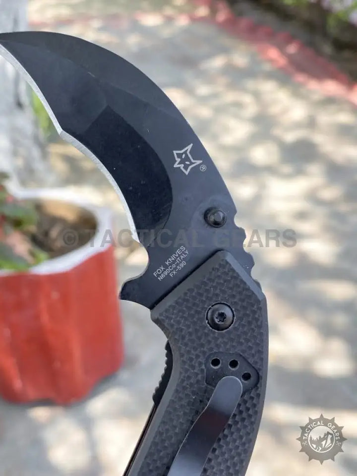 Black folding karambit with textured handle by Fox Knives, ideal for tactical use