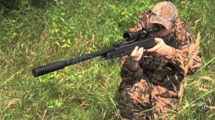 Hunter in camouflage aiming Gamo-Whisper Fusion Air Rifle 5.5mm with scope and suppressor