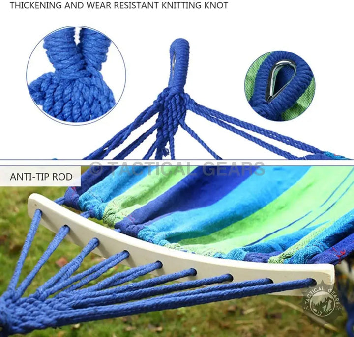 Colorful fabric hammock with wooden spread bars and blue rope suspension for outdoor relaxation