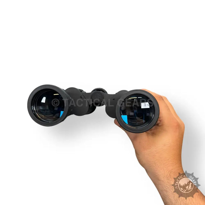 Black Bushnell 70x70 binoculars with blue lenses held in hand, includes case and box