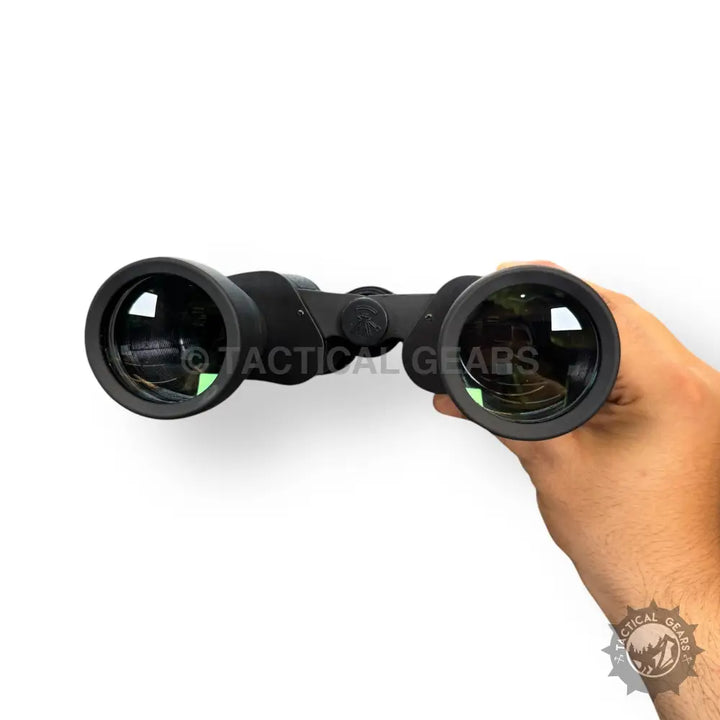 Black handheld Bushnell 70x70 zooming binoculars with green-tinted lenses for outdoor viewing