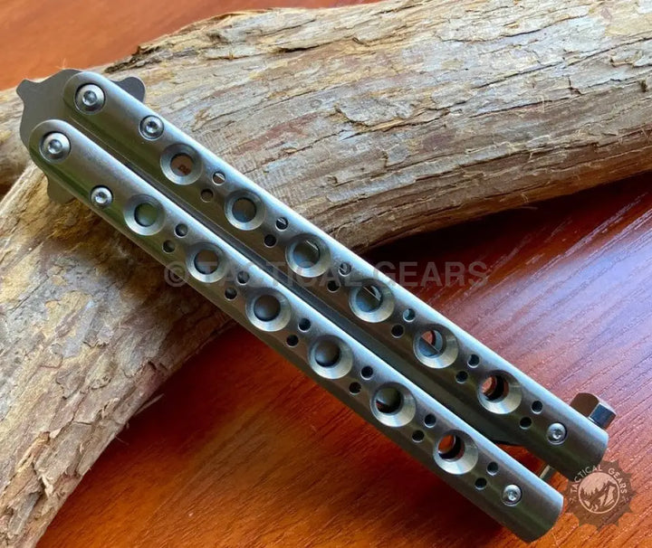 Gray butterfly knife silver steel with circular cutouts on handles for precise control