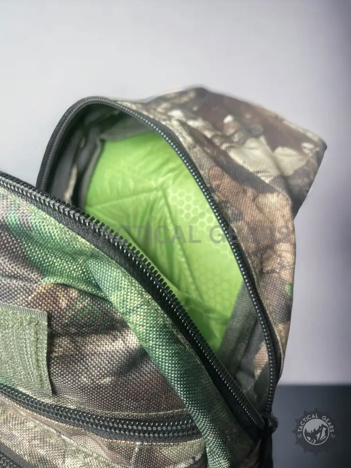 Camo hunting sling bag with open zippered compartment revealing bright green interior
