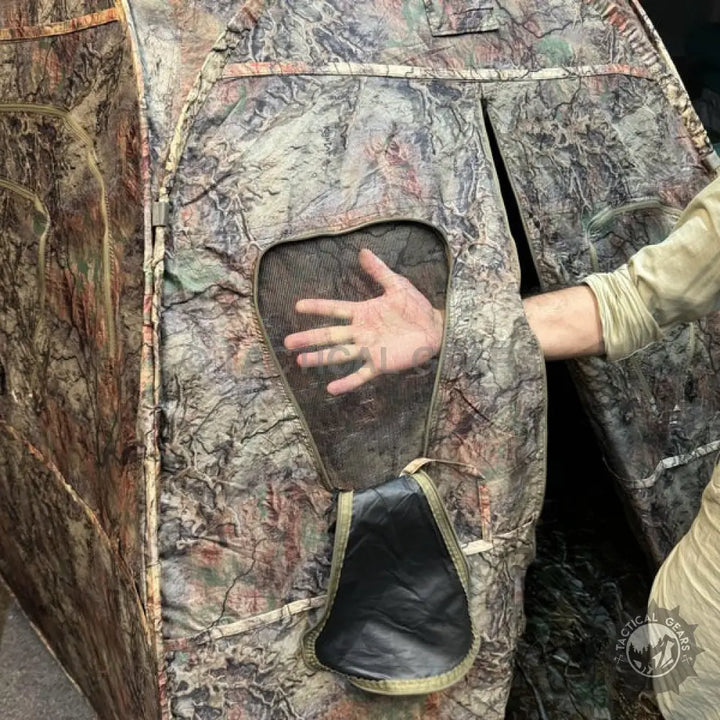 Camouflage hunting tent with mesh viewing window and open entry flap for hunting