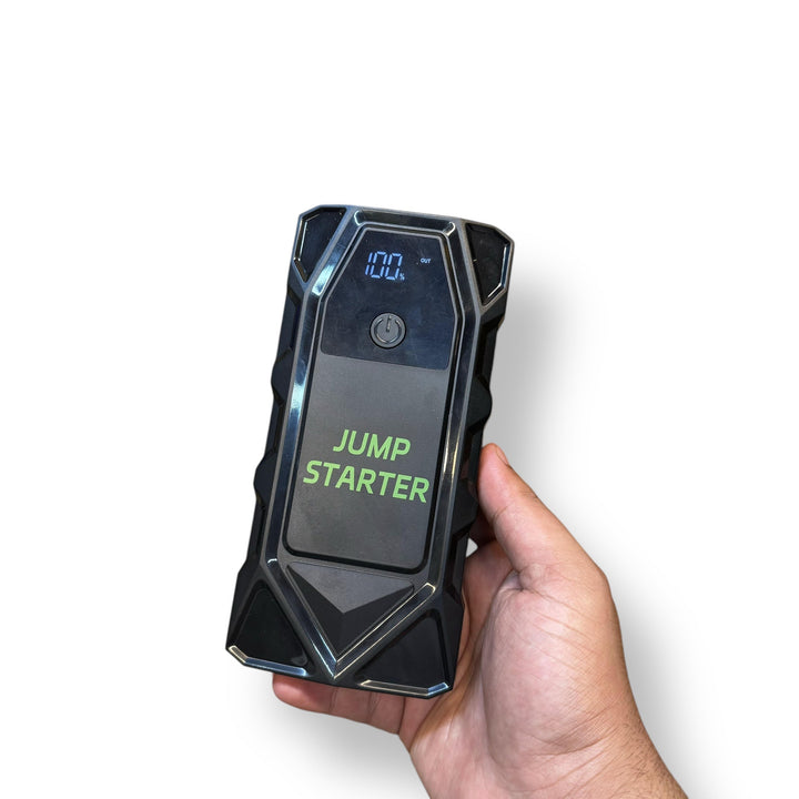 Hand holding a black Car Jump Starter with Tire Inflator and digital display