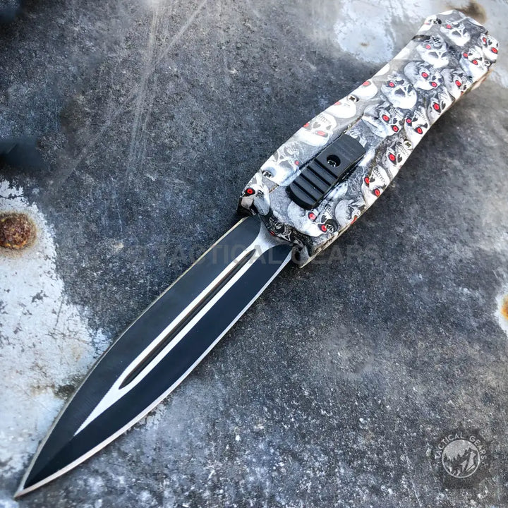 Combat OTF knives with black double-edged blade and skull-patterned handle in carbon fiber