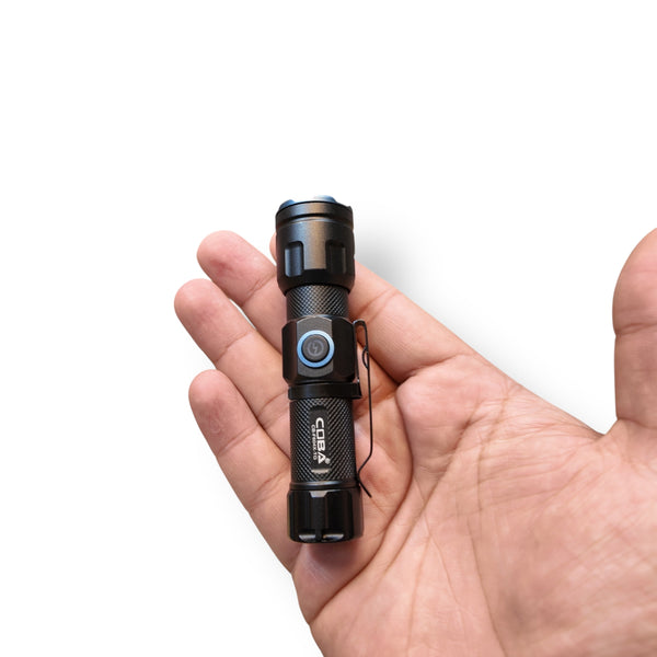 Coba Mini Rechargeable LED Flashlight held in hand, compact black with blue power button