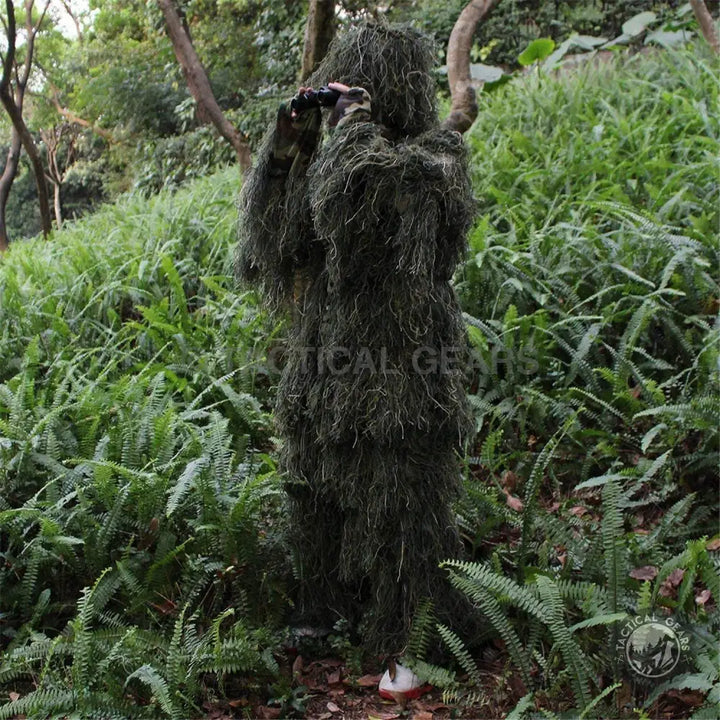 Person in camouflage forest hunting ghillie suit holding binoculars for wildlife photography