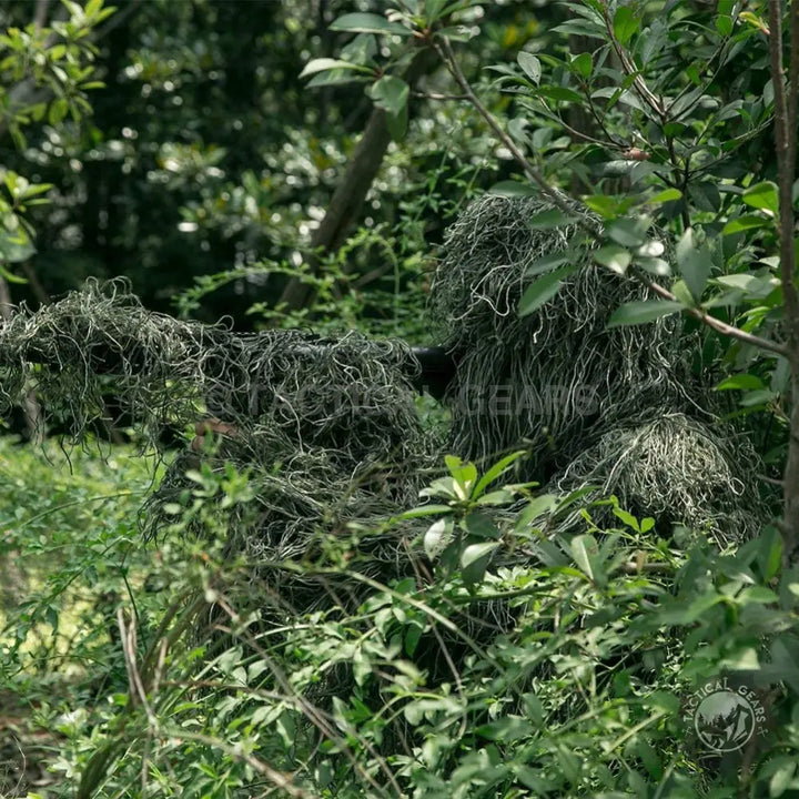 Person in camouflage forest hunting ghillie suit blending with dense foliage for wildlife photography