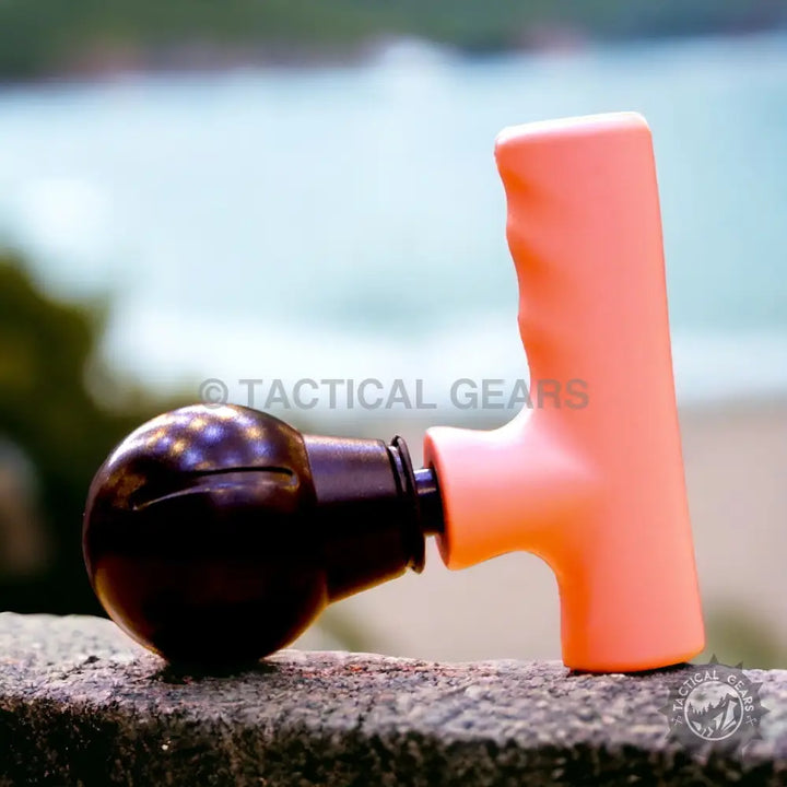 Mini Fascial Gun in coral with spherical black attachment for muscle relief