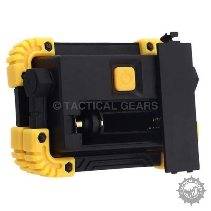 Portable black and yellow rechargeable flood light with open battery compartment for work sites