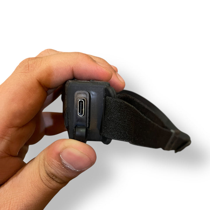 Person holding a flexible LED strip headlamp with USB-C charging port for outdoor use