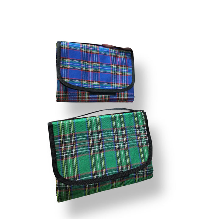 Foldable picnic sheet with blue and green plaid designs, black trim, and handle for person picnic