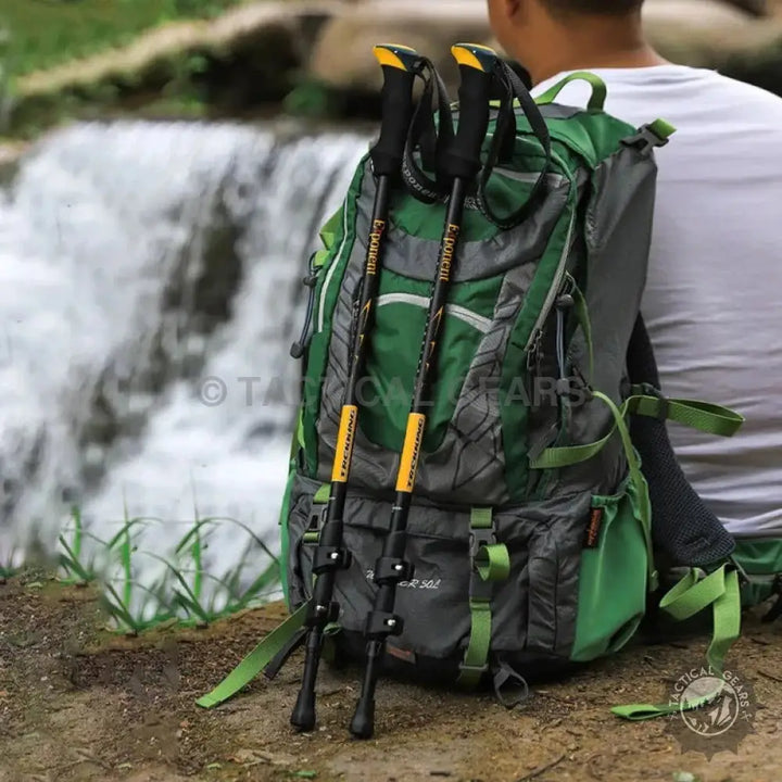 Green hiking backpack with attached trekking sticks for outdoor adventures