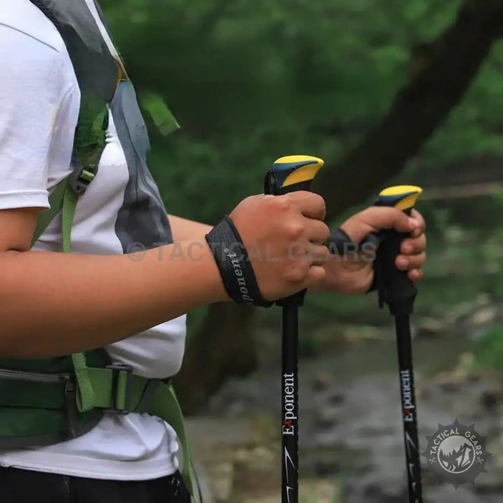 Person holding two black trekking sticks with yellow accents for Folding Hiking Stick product