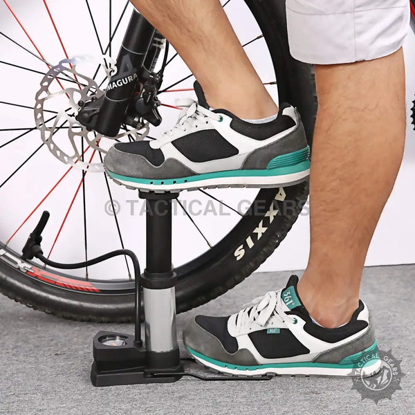 Person using foot-operated portable mini tire pump to inflate bicycle tire