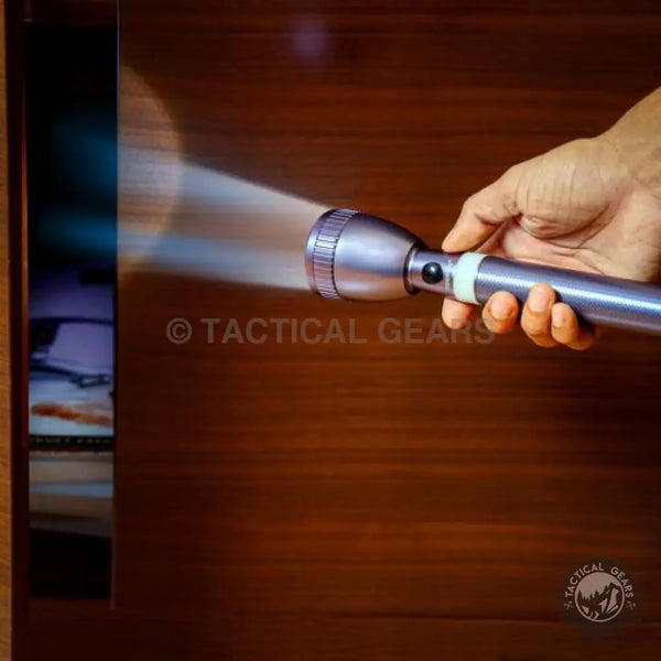 Silver-colored metal LED flashlight with black power button and glow-in-the-dark ring emitting bright light