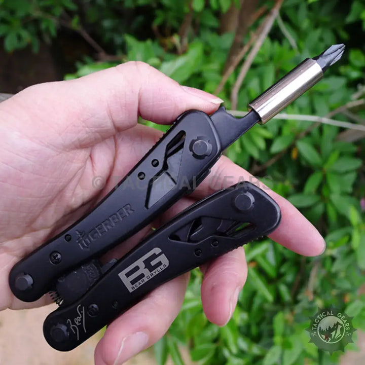 Gerber Bear Grylls Ultimate multi-tool with black tactical design, knife blade, screwdriver bits, and BG logo on handle