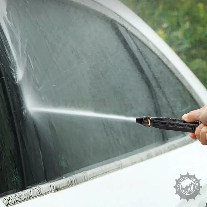 Person holding high pressure water nozzle to wash car with hose pipe