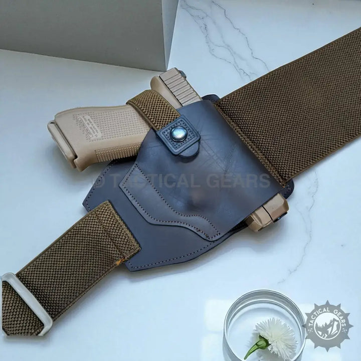 Tan handgun in dark grey leather belly band waist holster on khaki web belt