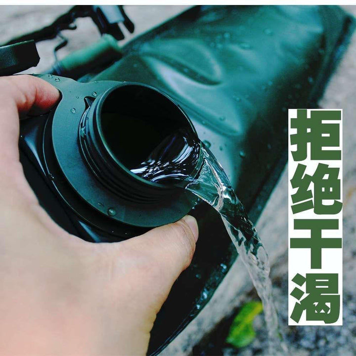Dark green KMS Water Camel Pack with shoulder strap being squeezed to dispense water