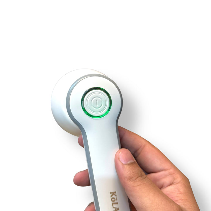 Hand holding a Kolax Lint Remover with white and grey fabric shaver and green power button