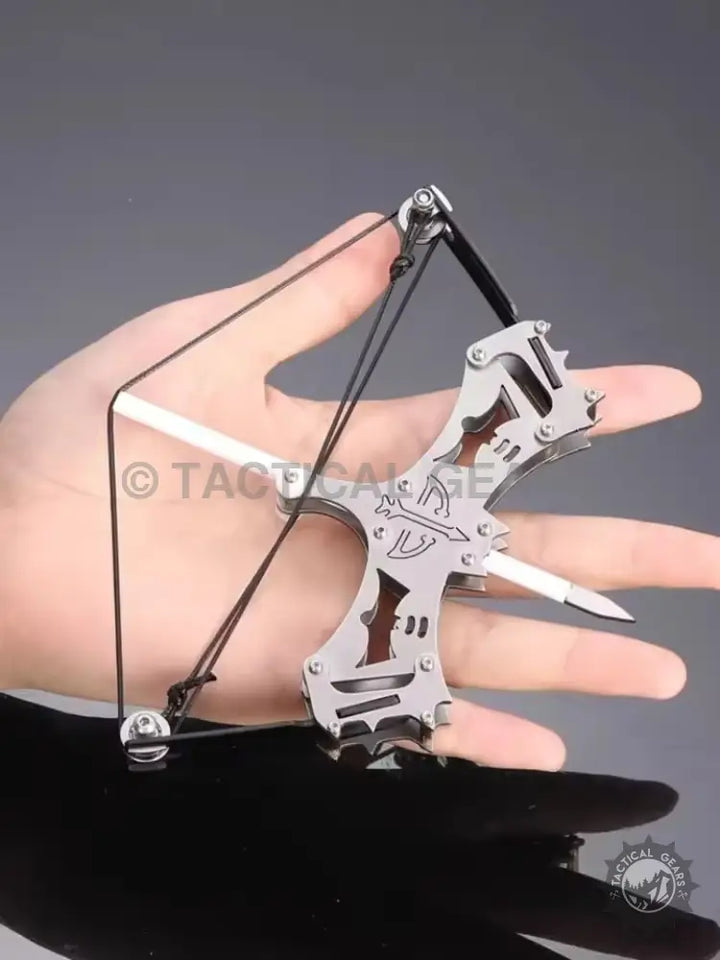 Mini compound bow held in hand showing compact metal design and pointed arrow