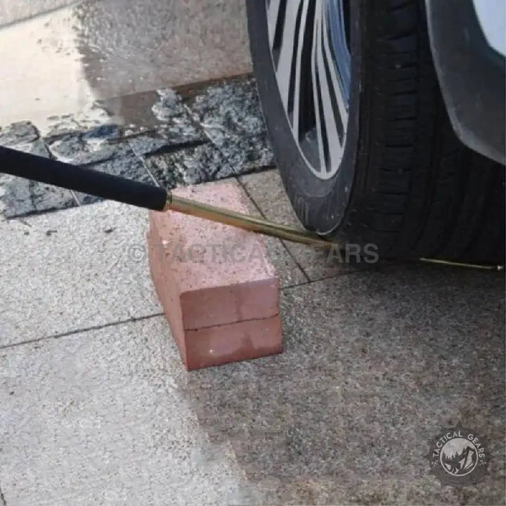 5.11 Self Defense telescoping metal baton with PVC material resting on brick near car tire