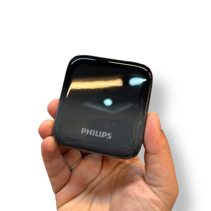 Hand holding shiny black Philips smart plug, ideal for fast charging power bank use
