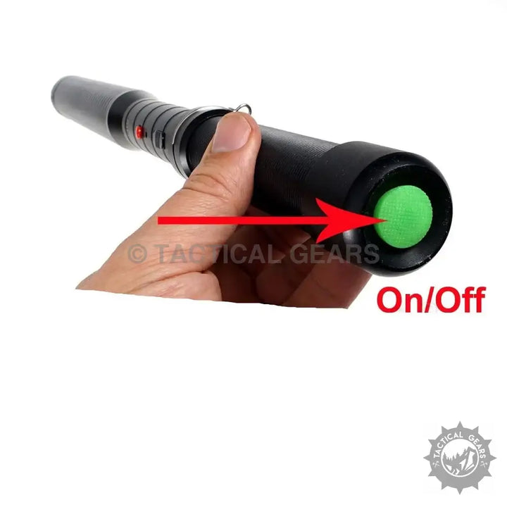Hand holding a black flashlight with green on/off button for Paralyzer High Voltage Pulse Batons 510-FZ