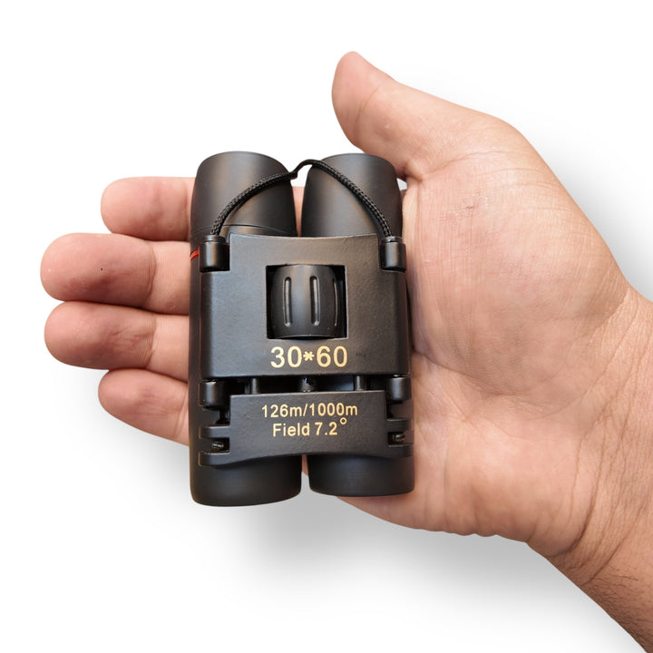 Pocket size mini binoculars held in hand, compact black binoculars for travel and outdoor use