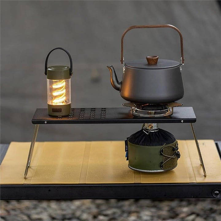 Black camping kettle on portable camping light with built-in Bluetooth speaker and tripod stand