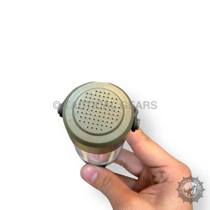 Hand holding olive green camping light with built-in Bluetooth speaker and speaker grill
