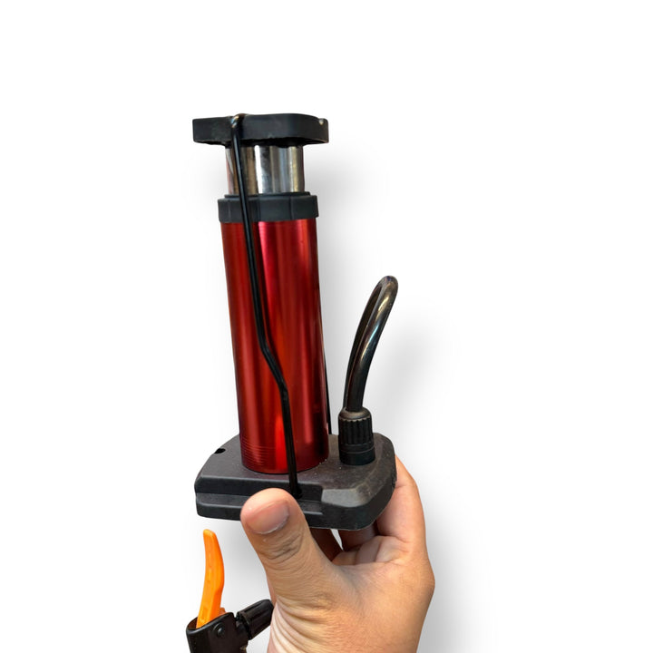 Red and black portable imported mini foot pump with hose and orange lever for inflation