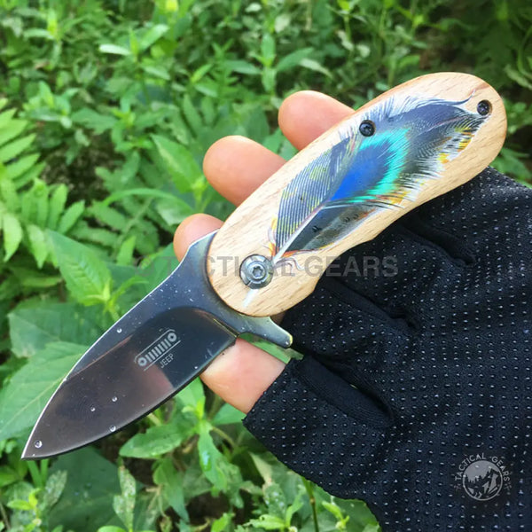 Portable mini lock folding knife with light wood handle and colorful feather design blade