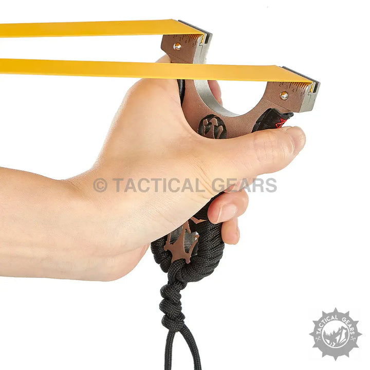 Hand holding a powerful laser hunting slingshot with yellow flat bands and black paracord strap