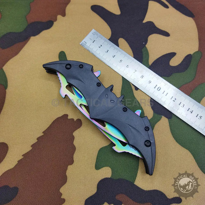 Black bat-shaped folding pocket knife with rainbow-colored stainless steel blade