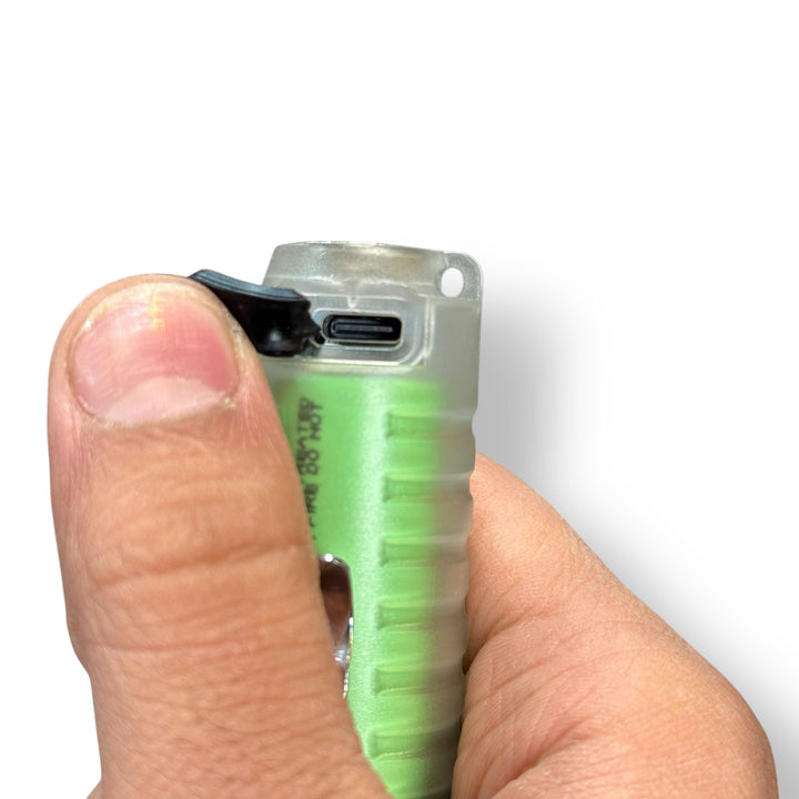 Person’s hand operating a transparent usb rechargeable flashlight with visible green battery