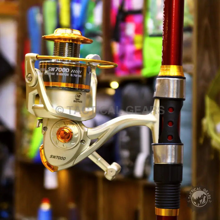 Gold and silver fishing reel attached to a red retractable fishing rod set