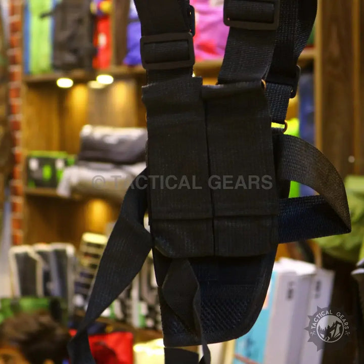 Black shoulder holster with adjustable straps and multiple pouches for tactical use