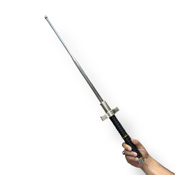 Person holding a retractable silver metal military baton with black textured handle