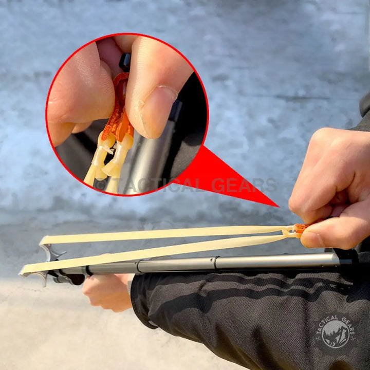 Person holding telescopic long rod slingshot with orange pouch and small projectiles